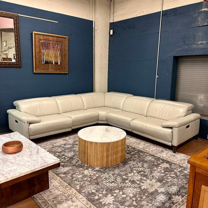 White sectional sofa in a room with blue walls, a round wooden coffee table, and decorative elements.