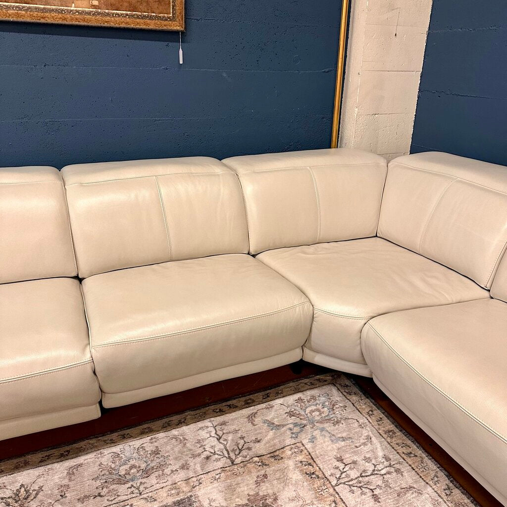 Beige sectional sofa against a blue wall with a decorative rug on the floor.