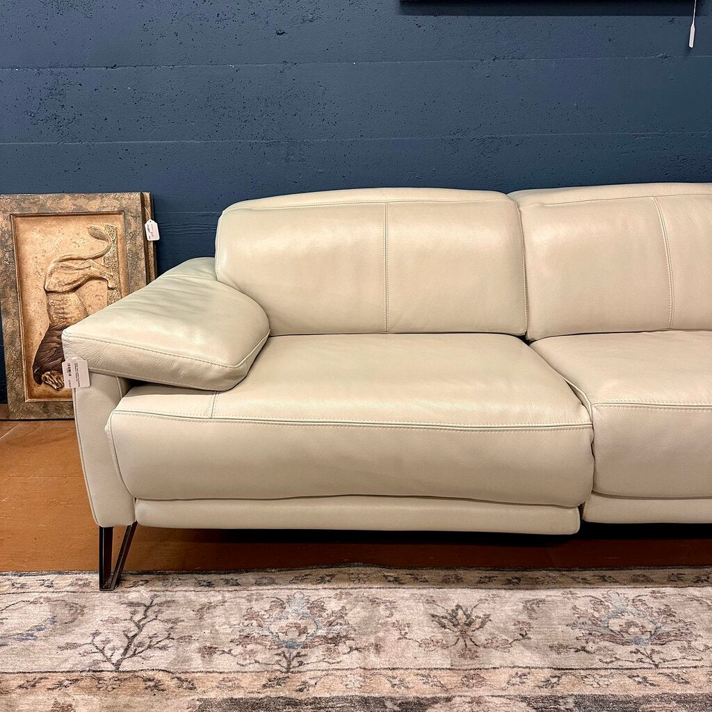 Beige leather sofa against a blue wall with a decorative piece on the left.