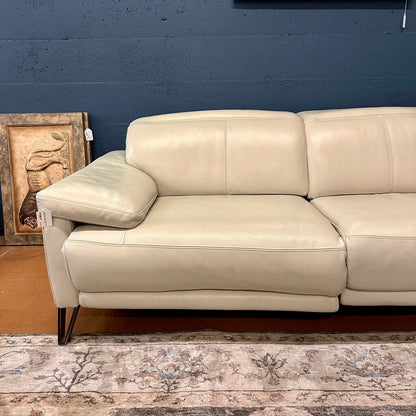 Beige leather sofa against a blue wall with a decorative piece on the left.