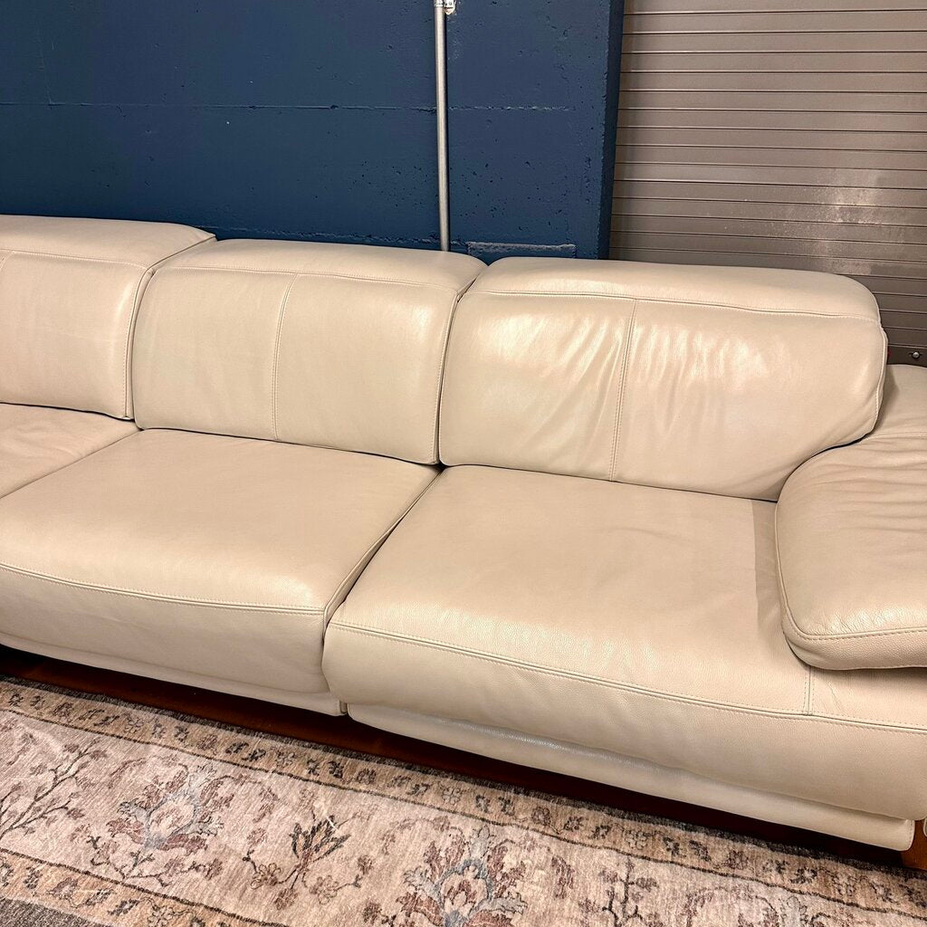 Beige leather sofa against a blue wall
