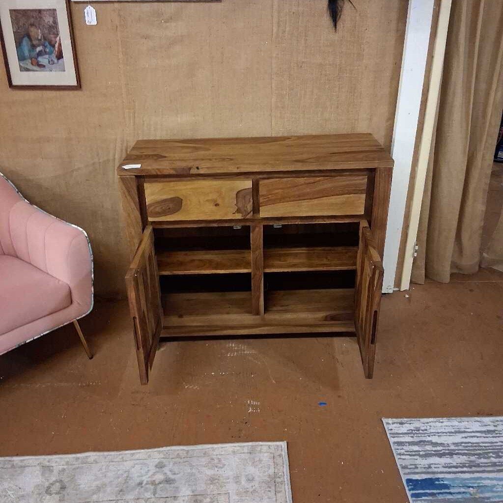 Wooden cabinet with open doors in a room with a pink sofa and framed picture on the wall.