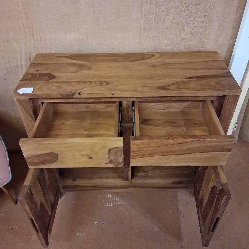 Wooden TV stand with a shelf and a small drawer against a plain wall.