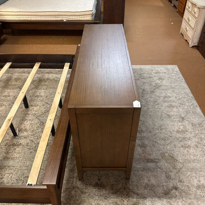 Wooden bed frame with mattress on a carpeted floor