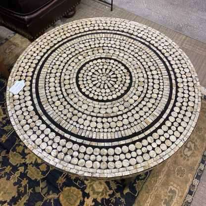 Round mosaic table with concentric circle design on a patterned rug