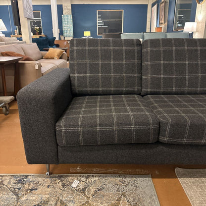 Gray plaid sectional sofa in a showroom setting with other furniture.