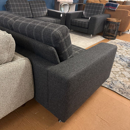 Gray upholstered sofa in a showroom setting with other furniture.