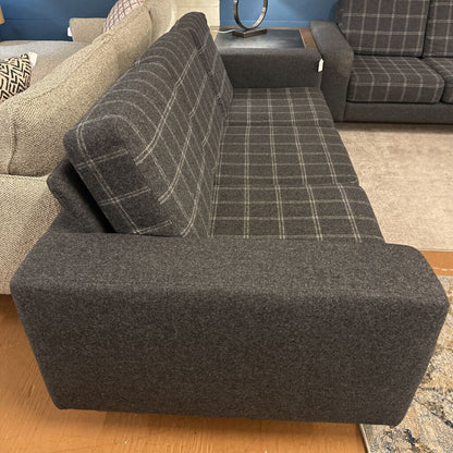 Gray plaid sofa in a living room setting with another sofa and decorative items.