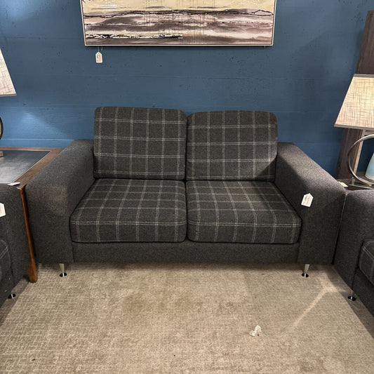 Gray plaid sofa in a room with a blue wall and a lamp.