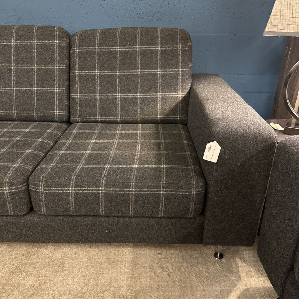 Gray plaid sofa against a blue wall with a lamp in the corner.
