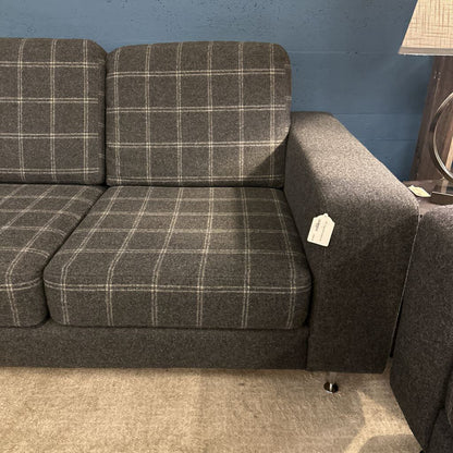 Gray plaid sofa against a blue wall with a lamp in the corner.