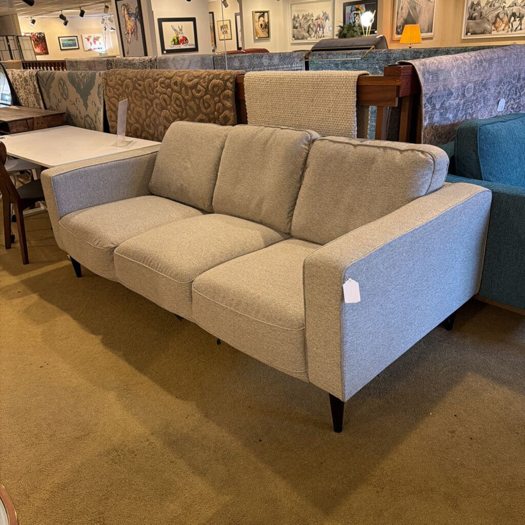 Beige sofa with a price tag in a furniture store setting