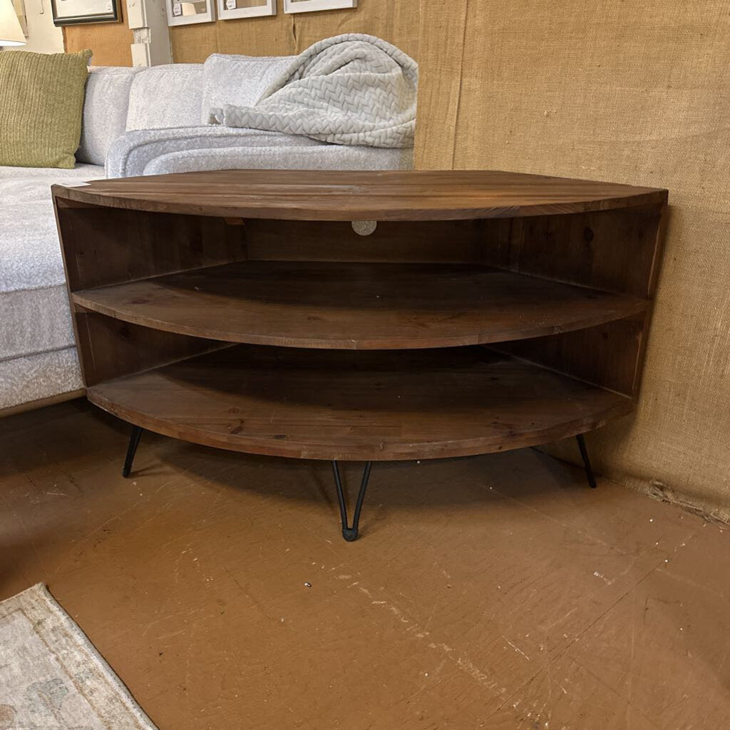 Wooden corner shelf in a room with a sofa and textured wall.