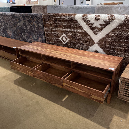 Wooden entertainment console with drawers in a showroom setting
