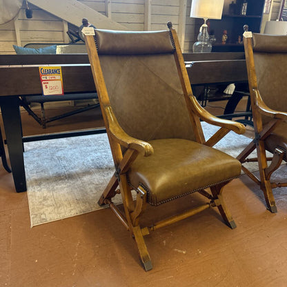 Brown leather chair with wooden frame on a brown floor.