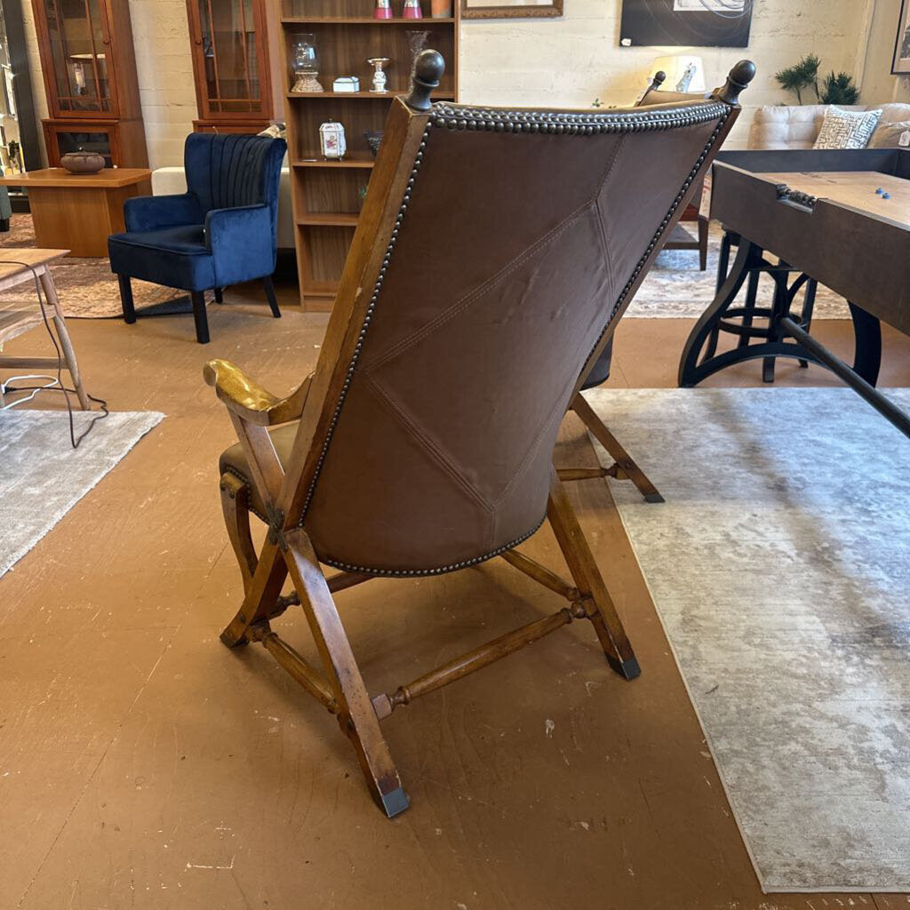 Brown leather armchair in a room with wooden floor and furniture.