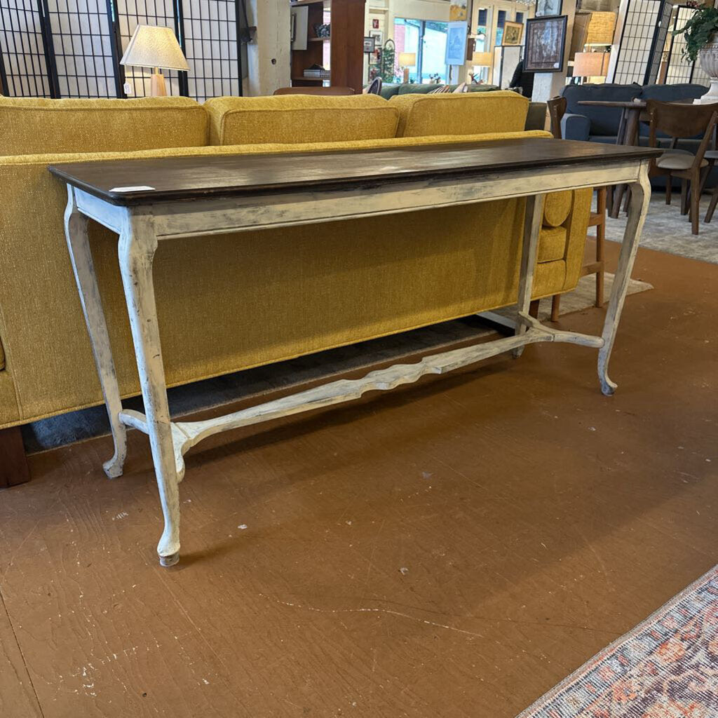 Vintage-style console table in front of a yellow sofa in an indoor setting