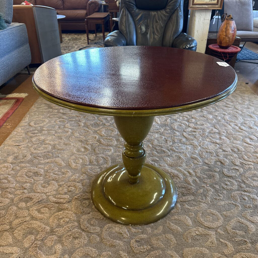 Wooden side table with a green base in a room setting
