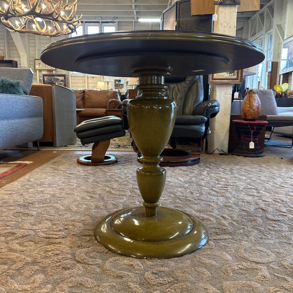 Decorative table with a green base and black top in a furniture store setting