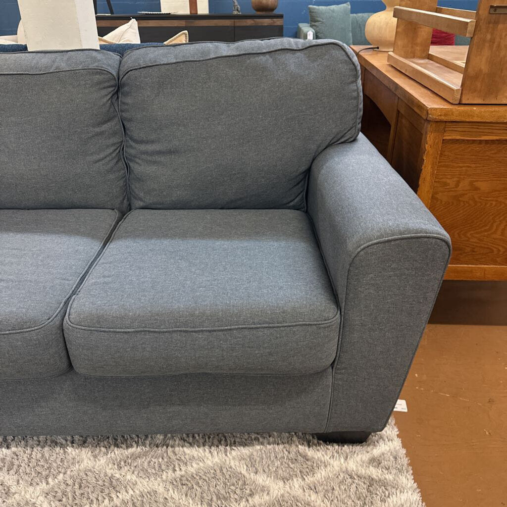 Gray sofa in a room with wooden furniture and a blue wall.