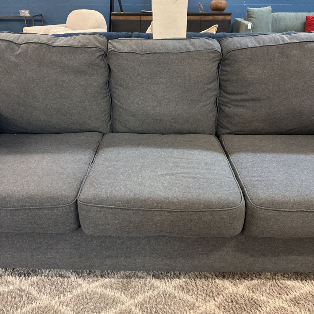 Gray sectional sofa in a room with a blue wall and other furniture.