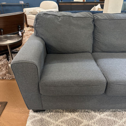 Gray sofa in a room with a rug and furniture.