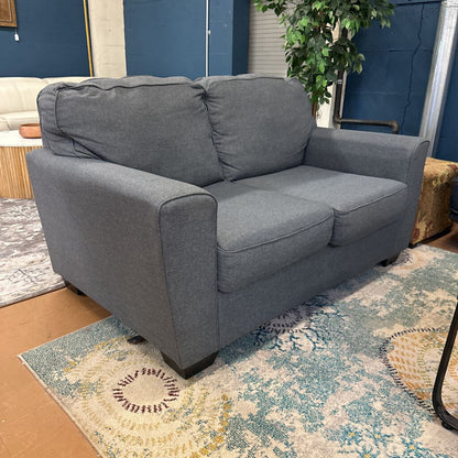 Gray sofa in a room with a patterned rug and plant