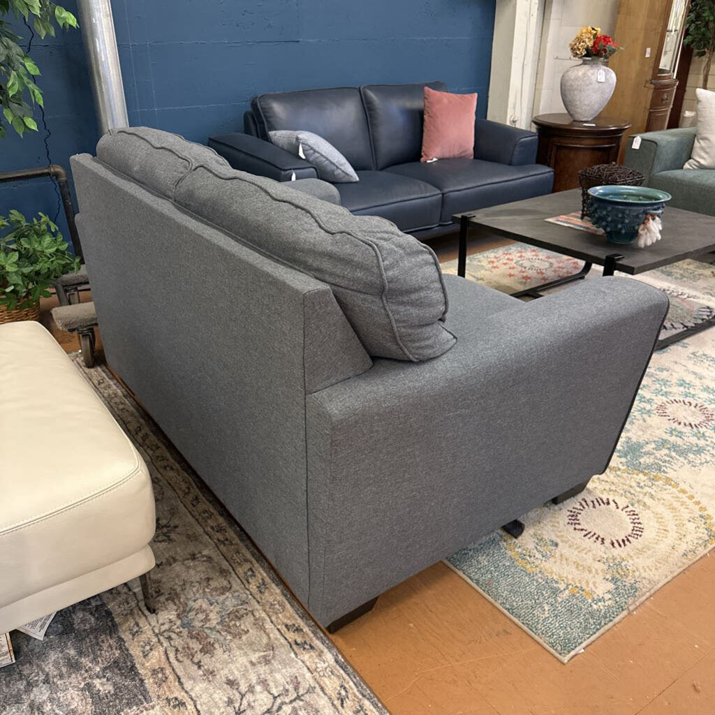 Gray sofa in a living room with a blue wall and decorative items.