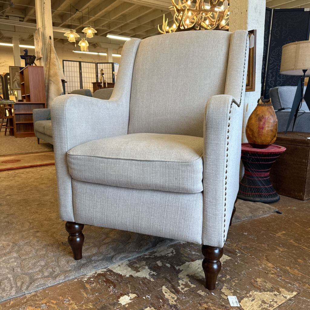 Gray armchair in a showroom setting with other furniture and decor items.