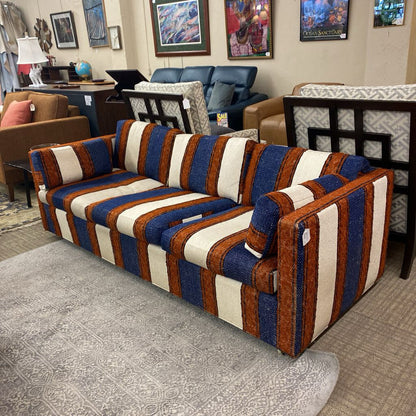 Striped sofa with blue, brown, and white pattern in a room with furniture and decor.
