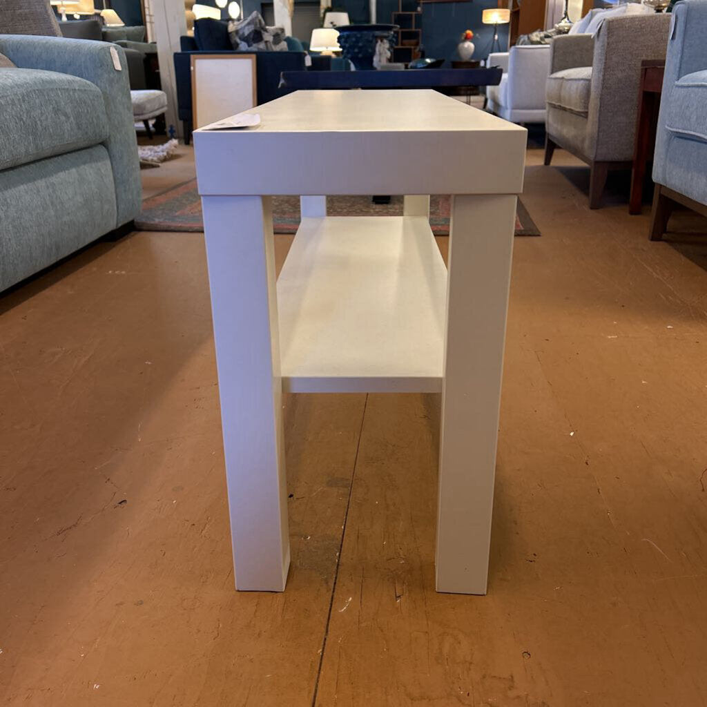 White table in a furniture store setting with chairs and other tables in the background.