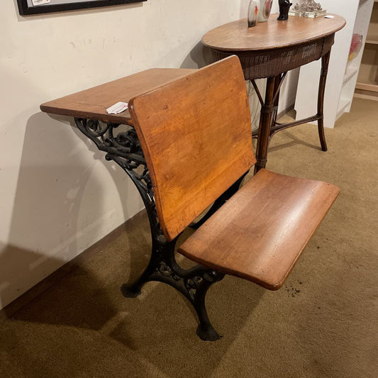 Vintage wooden school desk with metal legs against a plain wall.