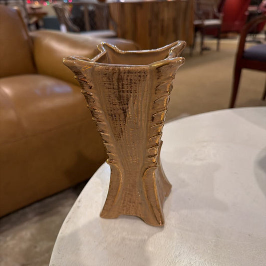 Bronze vase on a table with a blurred background of a room interior.