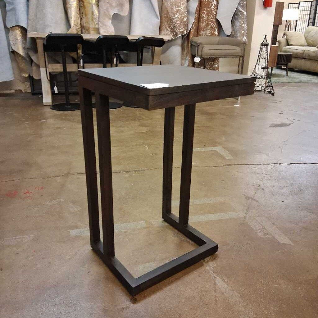 Wooden side table on a concrete floor with a blurred background