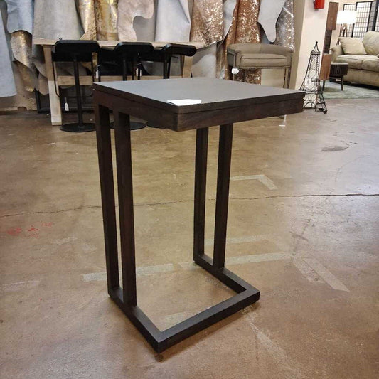 Wooden side table on a concrete floor with a blurred background