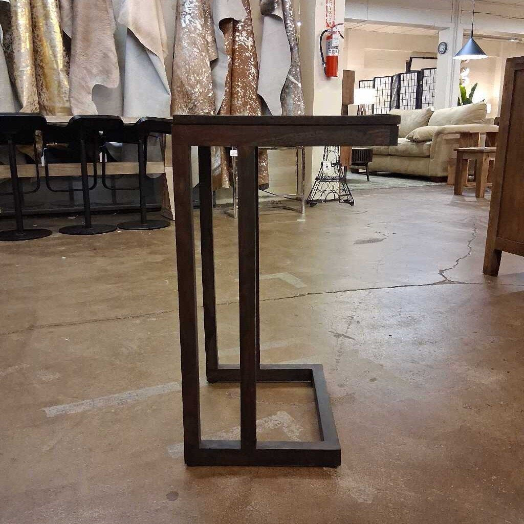 Wooden table base in a showroom setting with furniture in the background