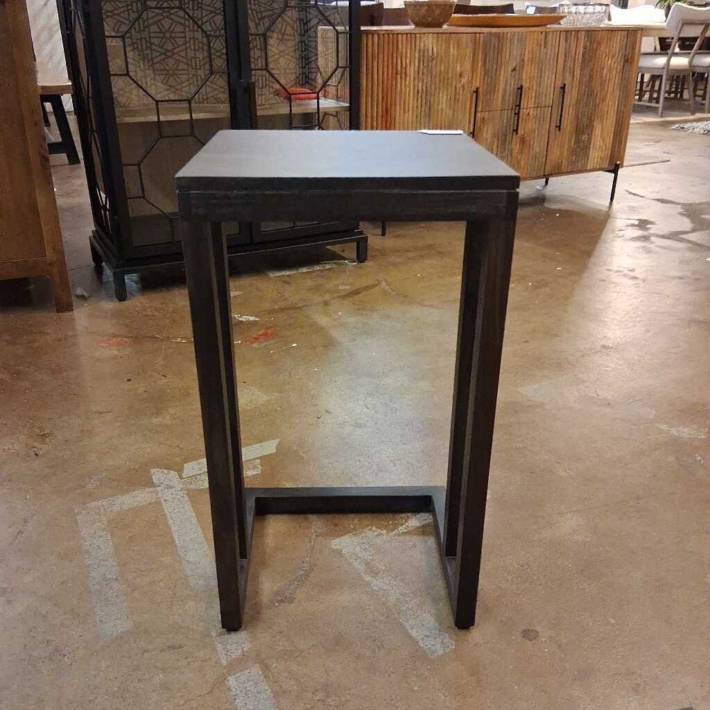 Small black metal table on a concrete floor with blurred background