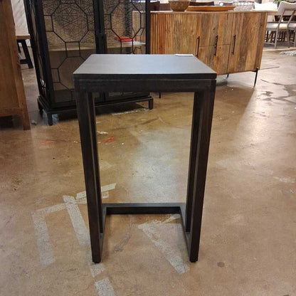 Small black metal table on a concrete floor with blurred background