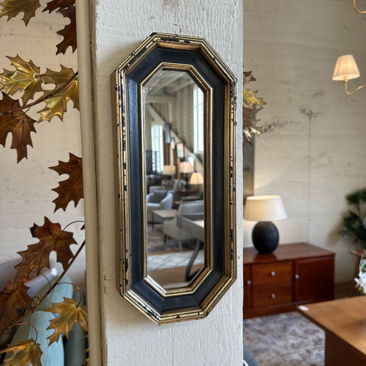 Decorative mirror with gold leaf accents on a textured wall