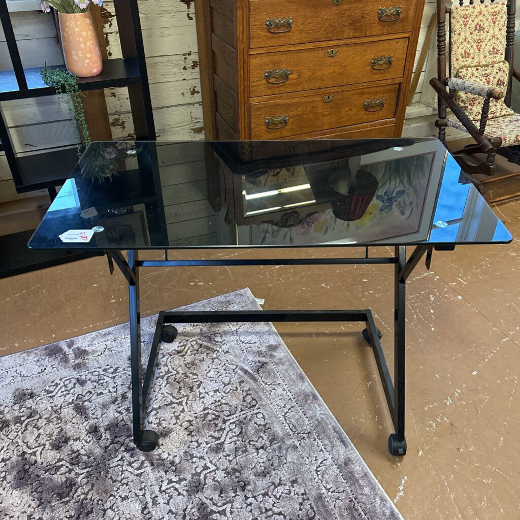 Black glass table with metal legs on a wooden floor