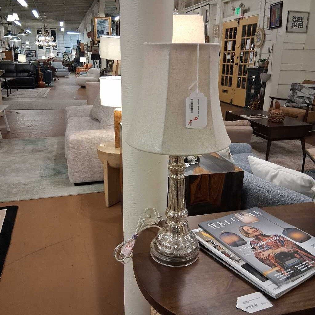Furniture store interior with a lamp on a table and a magazine.