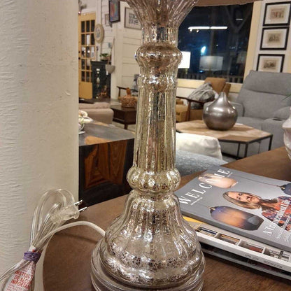 Mercury glass table lamp on a wooden surface with a magazine in the background