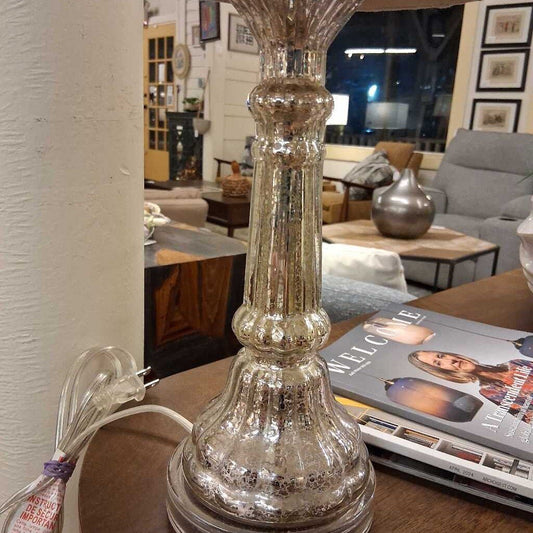 Mercury glass table lamp on a wooden surface with a magazine in the background