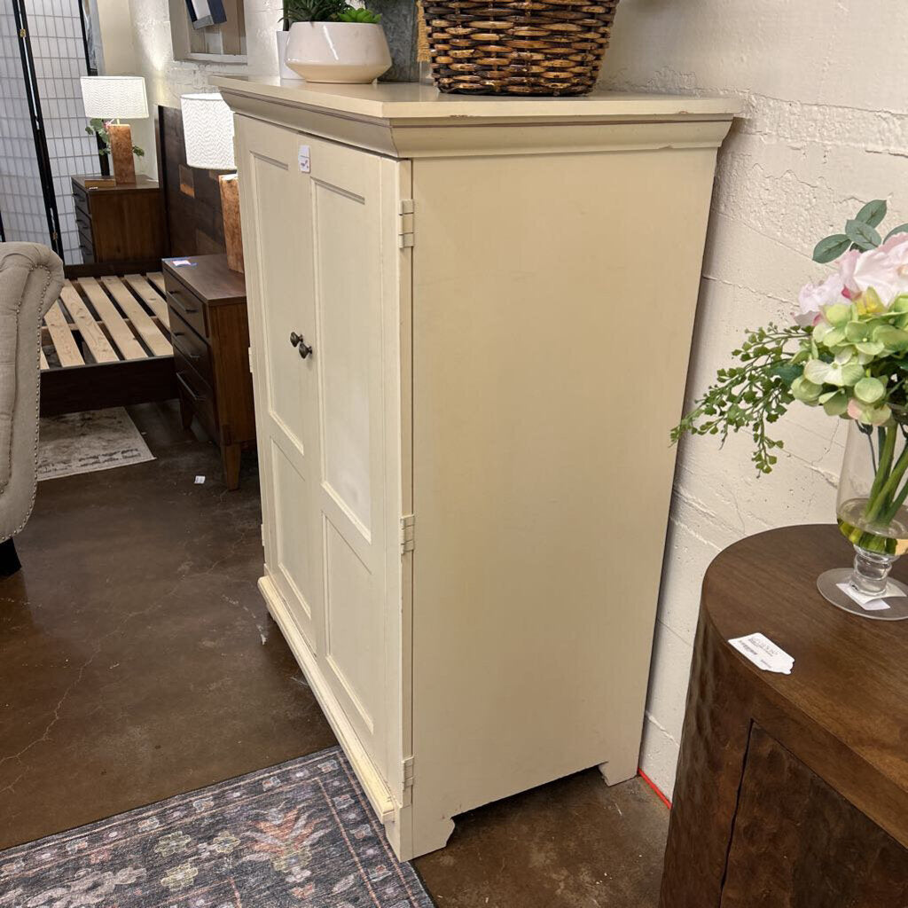 Beige cabinet in a room with a wooden table and decorative items.