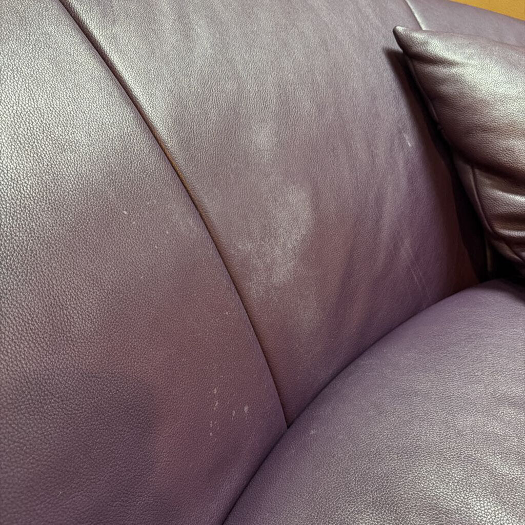 Close-up of a brown leather couch with visible wear and tear.