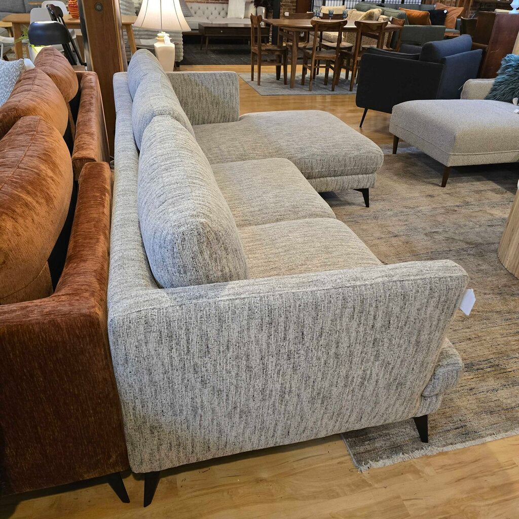 Gray sectional sofa in a furniture store setting with other sofas and chairs.