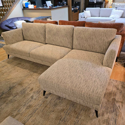 Beige sectional sofa in a room with other furniture.