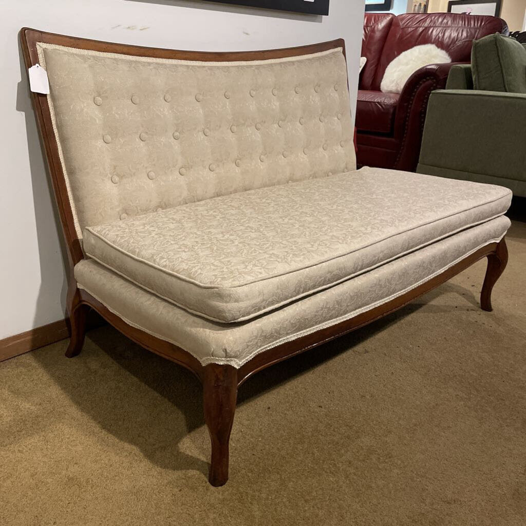 Ornate armless settee in cream damask fabric with button tufting and cabriole legs.