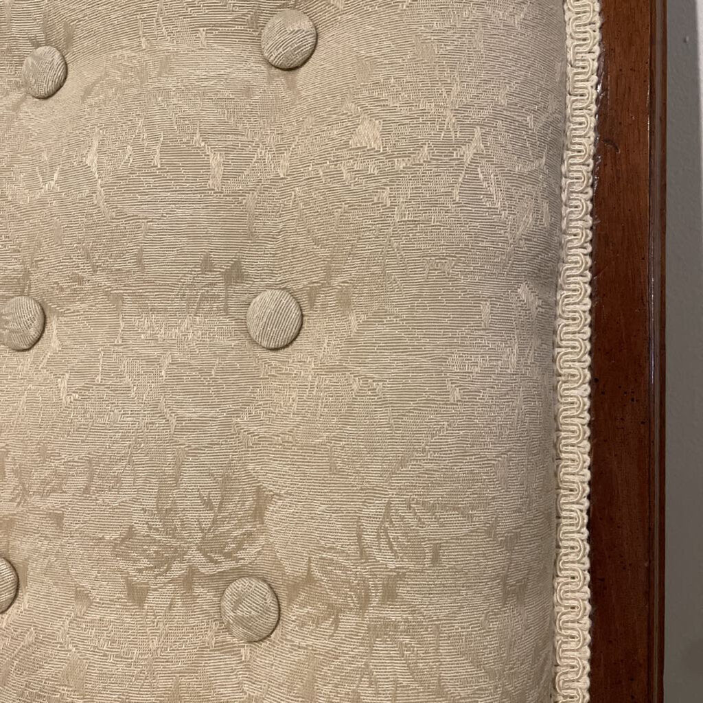 Ornate armless settee in cream damask fabric with button tufting and cabriole legs.