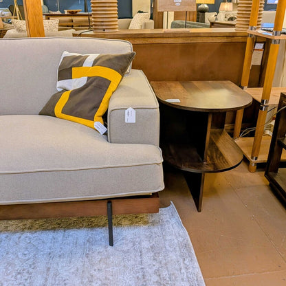 Gray sofa with a patterned throw blanket in a furniture store setting
